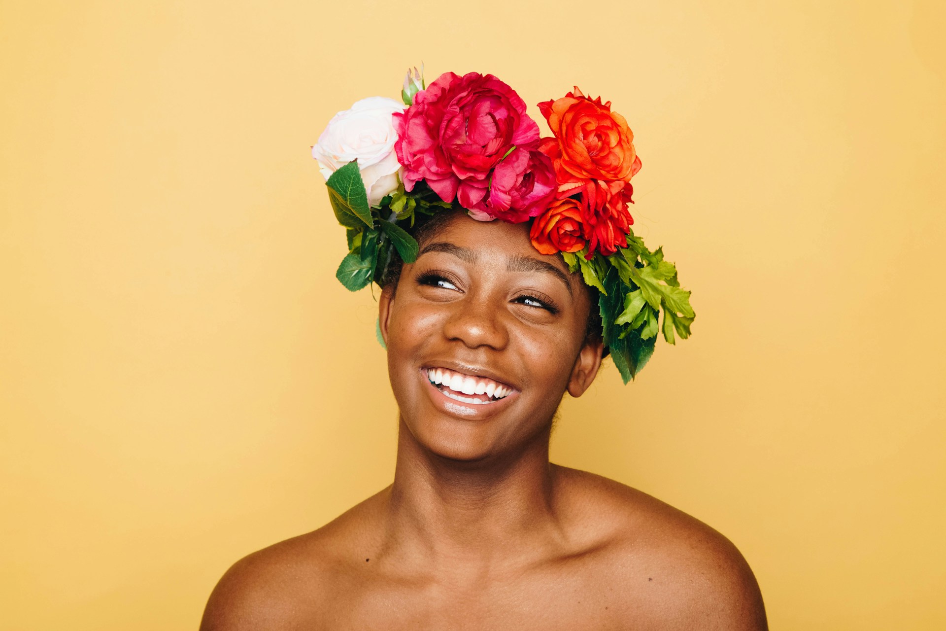 black woman smiling with flower crown on orange background